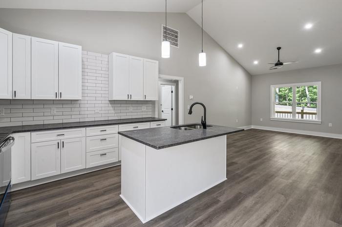 Kitchen with white cabinets, subway tile and a dark-top island at Hillcrest at Woodrun