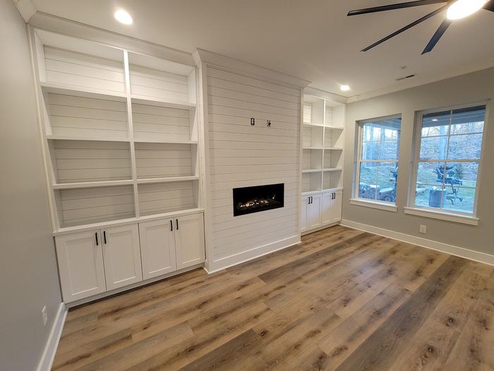 Living room with a shiplap fireplace wall and built-in shelving