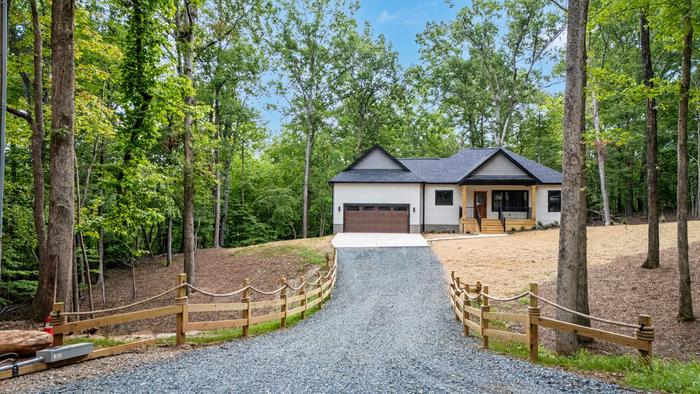 Gravel driveway with a split-rail fence leading to the Raven's Ridge custom home in Mt. Gilead, NC