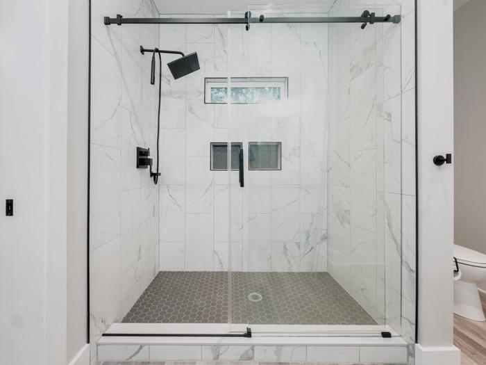 Walk-in shower with marble-look tile, glass door and black fixtures at Raven's Ridge